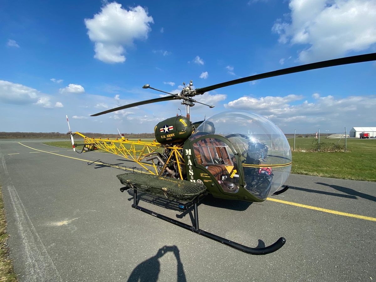 Bell 47 in MASH-Lackierung mit Kabinenkanzel und Krankentrage auf dem Vorfeld